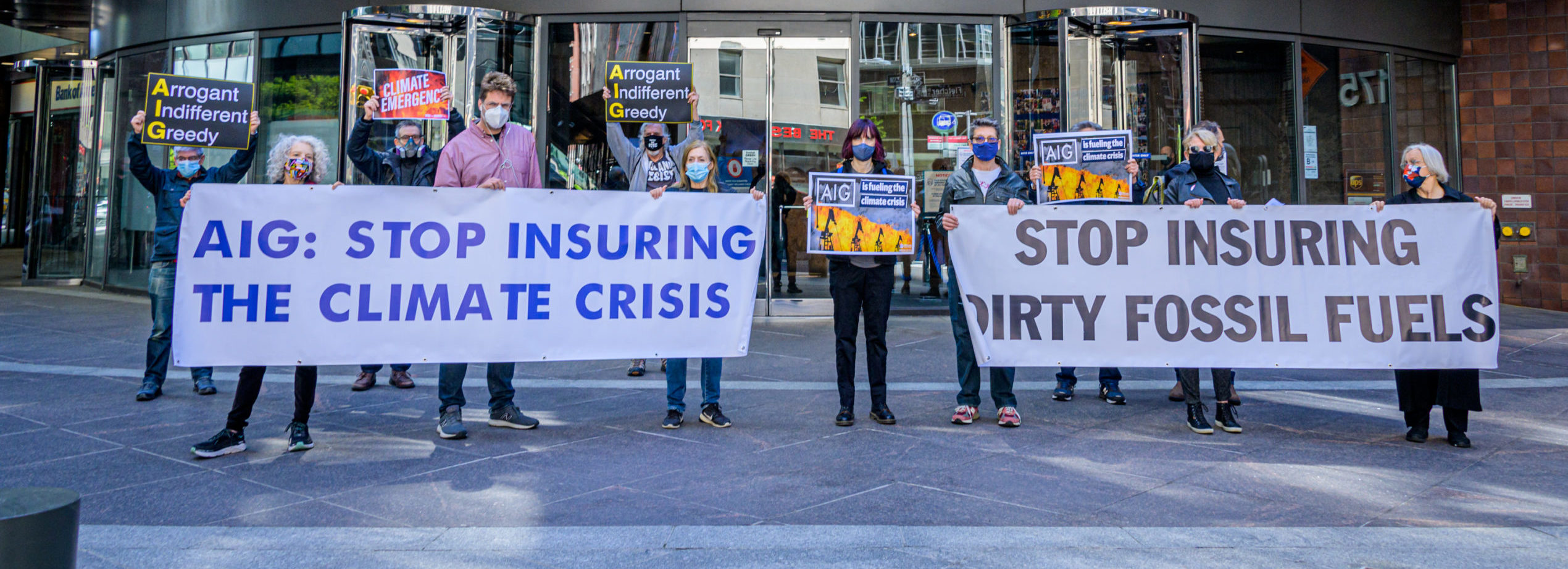 Activists stand in front of AIG's Headquarters with signs that read, 